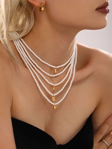Dettaglio di collana di perle a cinque strati con ciondoli geometrici dorati