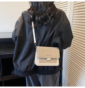 Detail of minimalist cream crossbody bag with Fashion & Bags text on textured leather