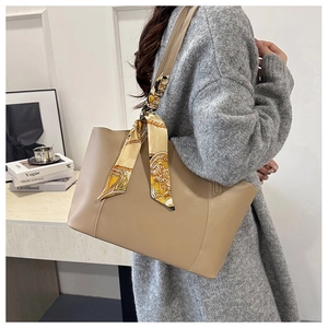 Detail of premium tote bag with decorative silk scarf handle on textured leather