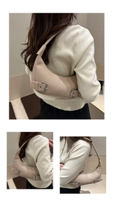 Detail view of beige crescent shoulder bag showing silver metal buckles and leather texture