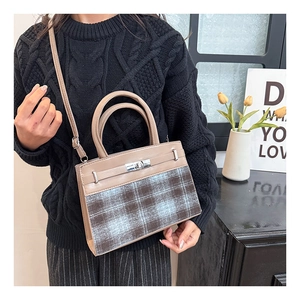 Detail view of khaki and checkered handbag styled with a knitted black sweater