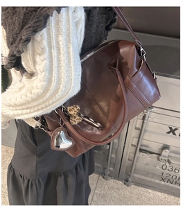 Deep brown tote bag with heart charm and leopard bow shown on model's shoulder