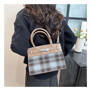 Detail of vintage plaid handbag with brown leather handle shown in a warm lifestyle setting