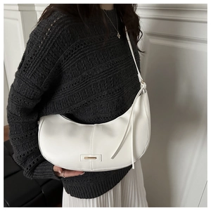 Sac hobo blanc avec boucle dorée porté avec un pull gris pour un look tendance chic