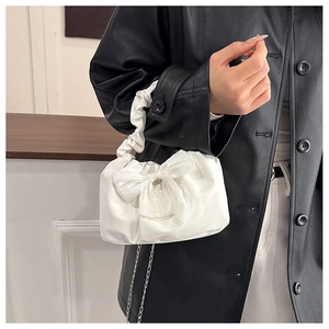 Close-up of white crossbody bag featuring a large bow and scrunchie style handle detail