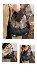 Detail view of black crescent bag with silver buckles and zipper closure on a model