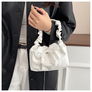 Detail of white pleated cloud handbag with large organza bow and metallic chain strap