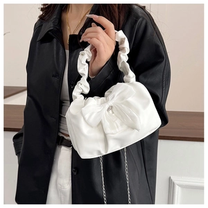 Detail of white pleated handbag with large bow and elegant silver chain strap