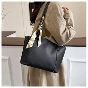 Detail of black trapezoidal tote bag with white contrast stitching and printed silk scarf