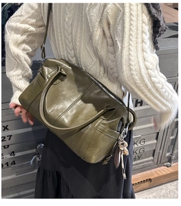 Olive green Boston bag made of oil wax leather being carried by a model in a casual style
