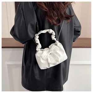 Détail du sac nuage plissé blanc avec nœud décoratif et bandoulière chaîne sur modèle