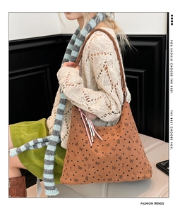 Sac hobo en velours côtelé marron avec motifs nœuds et cœurs porté par un mannequin