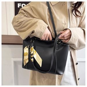 Detail of black matte leather tote bag with white contrast stitching and floral silk scarf
