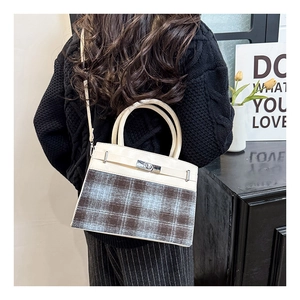 Detail of the chic patchwork handbag with plaid fabric and silver twist lock on a model