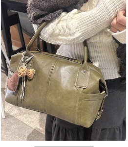 Close-up of green Boston bag with heart and leopard print charms in model's hand