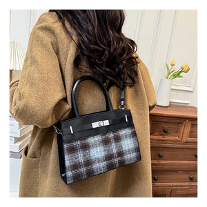 Détail du sac à main élégant en cuir noir et tissu écossais avec fermoir argenté carré