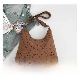 Détail du sac en velours marron avec motifs de nœuds noirs et breloque ours en peluche