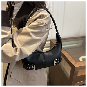 Detail of black leather hobo shoulder bag with silver buckles worn by a model