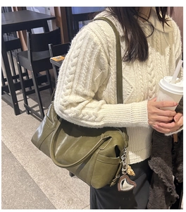 Olive green faux leather tote bag with heart charm shown on a cable knit sweater