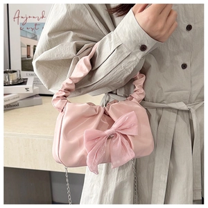 Detail of pink pleated handbag featuring a large organza bow and silver chain strap