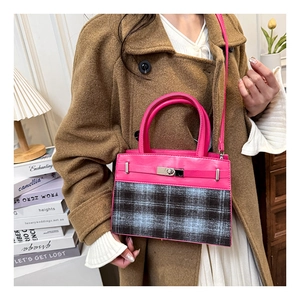 Detail of fuchsia leather and plaid patchwork handbag with silver twist lock and handle