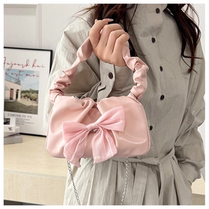 Detail of a pink sweet-style square bag featuring a large bow and pleated handle