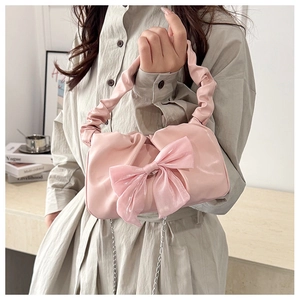 Detailed view of pink bow handbag with pleated handle and elegant metal chain strap