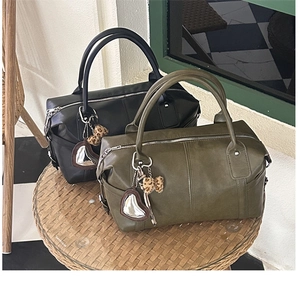 Detail of black and olive green leather Boston bags with heart mirror and leopard bow