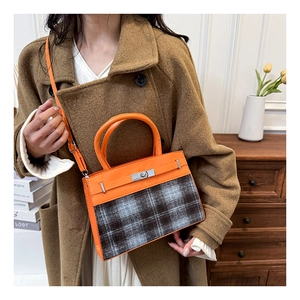 Detail of retro orange leather and grey plaid crossbody bag with silver twist lock buckle
