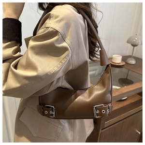Detail of a brown leather hobo bag with silver buckles and a minimalist shoulder strap