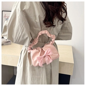 Close-up of pink pleated handbag with bow detail and silver metal chain strap