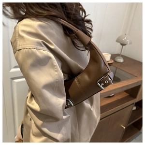 Detail einer braunen Leder-Schultertasche mit silberner Metallschnalle und Reißverschluss.