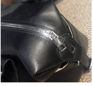 Close-up of black Boston bag with lychee texture and metallic silver zipper detail