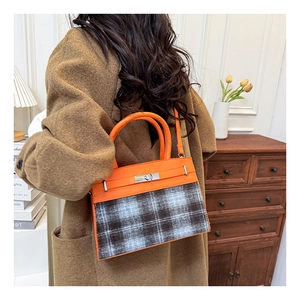 Detail of orange leather and plaid fabric Kelly bag with silver metal twist lock clasp