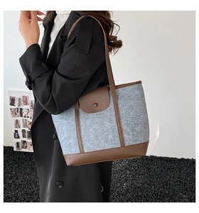 Detail of grey felt shoulder bag with brown leather straps and vintage snap button closure