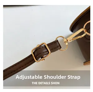 Détail de la bandoulière réglable en cuir marron foncé avec boucle en métal doré poli