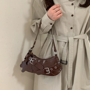 Sac sous le bras marron brillant avec boucles de ceinture et charm d'ours sur modèle
