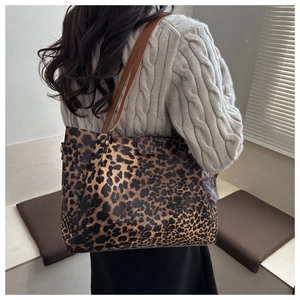 Rear view of a large leopard print tote bag with brown leather handles on a model