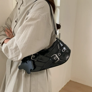 Chic black patent leather shoulder bag with buckle straps and a bear charm for Y2K style