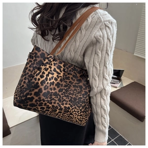 Close-up of leopard print tote bag with brown leather handles worn by a model