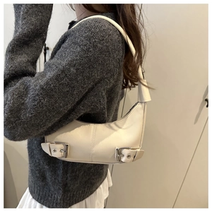 Detailansicht der cremefarbenen Tasche mit silbernen Schnallen am Schultergurt