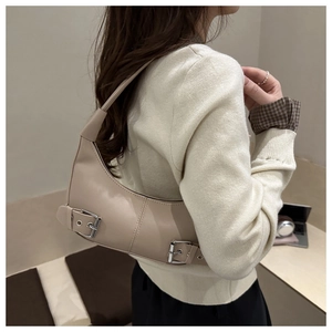 Detailansicht der beigen Achseltasche mit silbernen Metallösen und Riemenverzierung