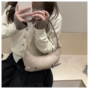 Detail of beige crescent hobo bag with silver buckle straps and sleek zipper closure