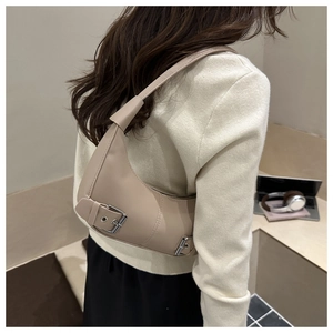 Beige halbmondförmige Achseltasche mit silberner Schnalle an der Schulter des Models