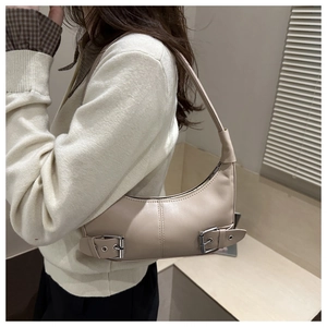 Detail showing beige moon-shaped shoulder bag with silver buckles and stitch textures