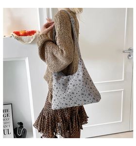 Sac fourre-tout gris en velours côtelé avec motifs nœuds et cœurs porté par un mannequin