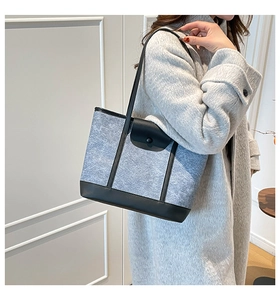 Detail of grey felt tote bag with black leather straps on a grey wool coat model