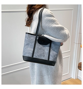 Detailed view of the large grey felt tote bag with black leather trim on a model's shoulder
