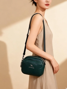 Détail du cuir grainé vert avec logo kangourou métallique sur un sac à bandoulière élégant