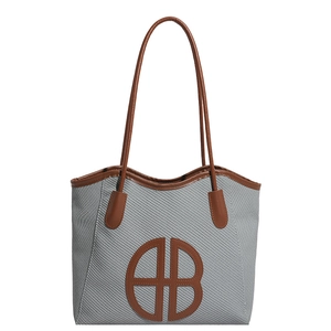 Minimalist woven tote bag with brown leather trim and circular AB logo patch